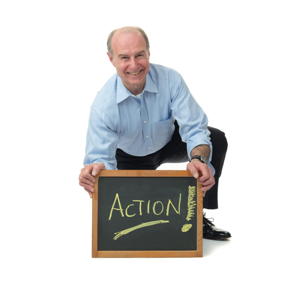 Friendly, casual image of Evan holding a small blackboard with the word "Action" on it.
