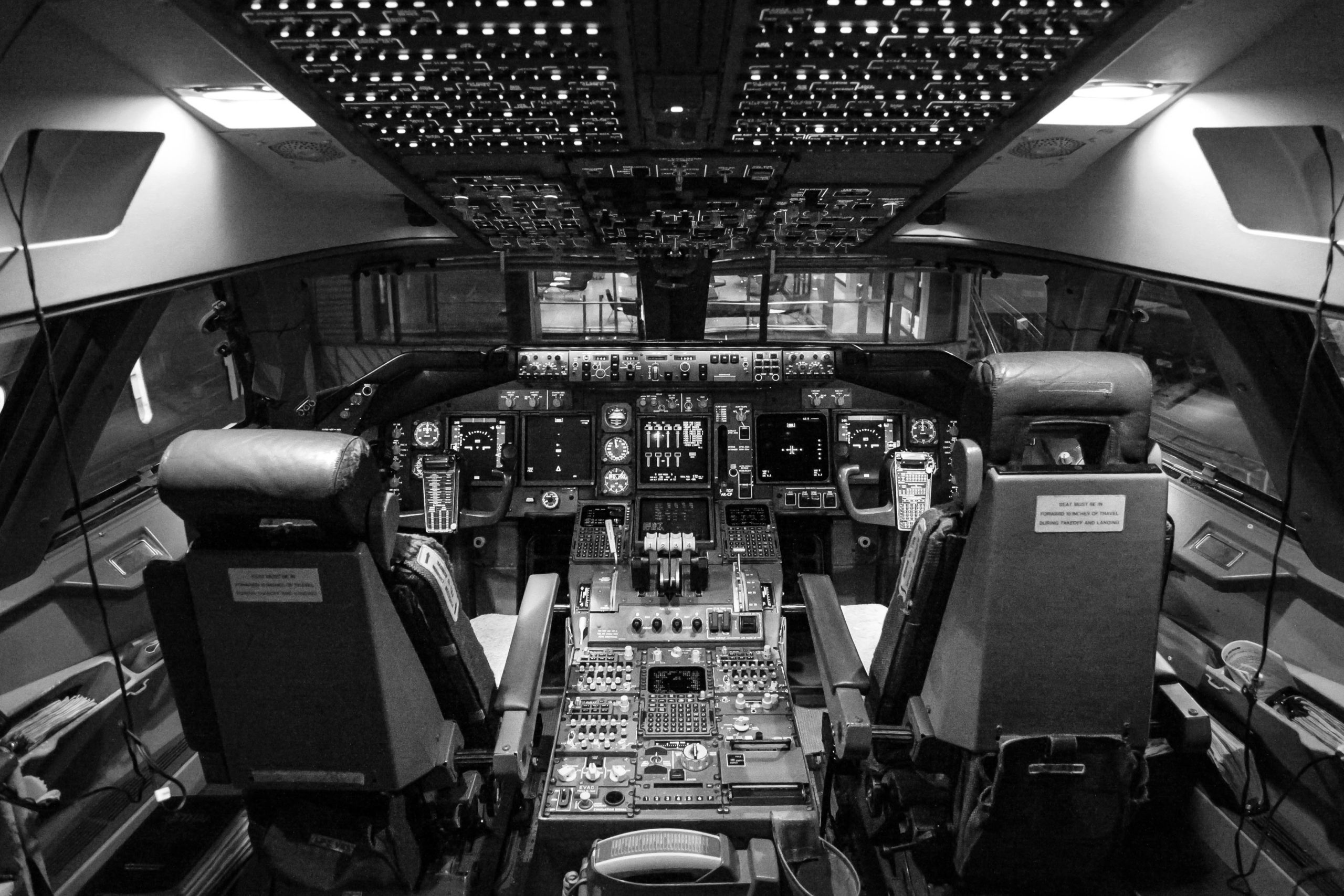 Black and white photo of the inside of a plane cockpit.